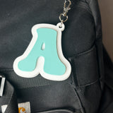 Black backpack with a turquoise 'A' keychain attached